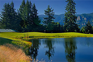 Pond on golf course with mountains in background.